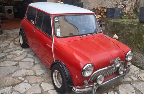 Austin Cooper de 1965 rouge à toit blanc, équipée de jantes larges et de quatre phares additionnels à l'avant.