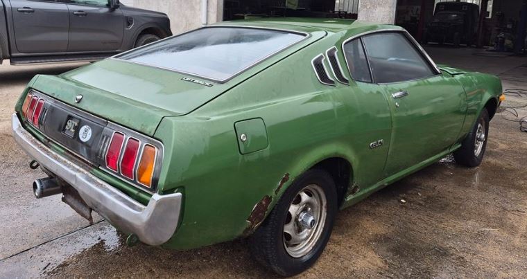 Toyota Celica Liftback de 1976 verte, photographiée de trois quarts arrière avec des traces de rouille sur les ailes.