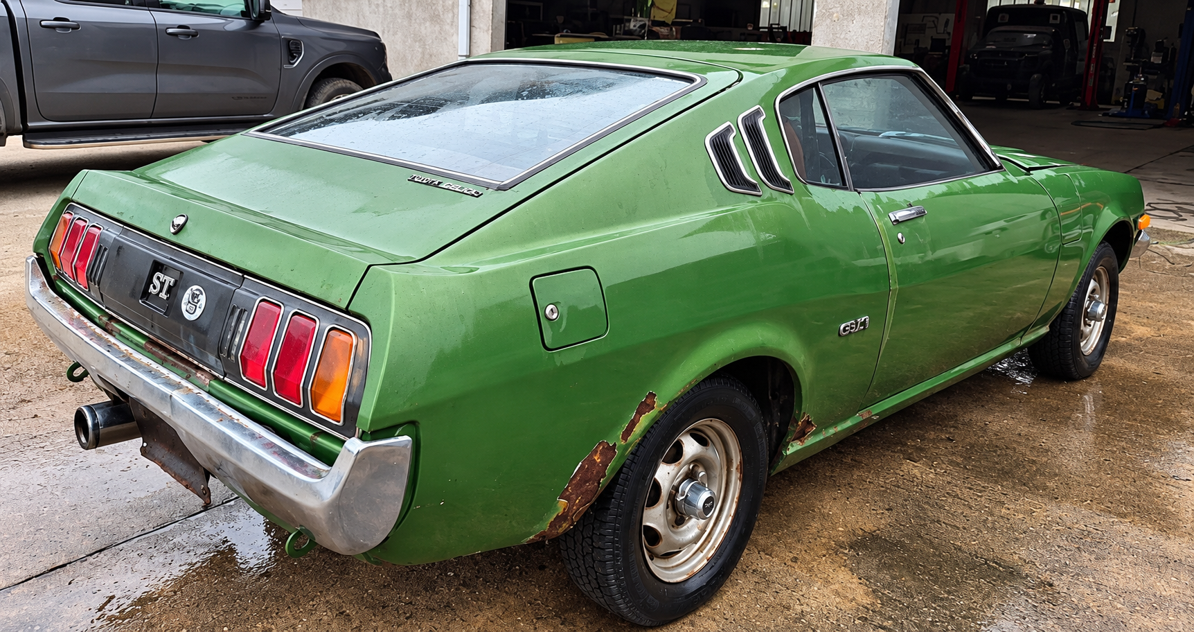 Toyota Celica Liftback de 1976 verte, photographiée de trois quarts arrière avec des traces de rouille sur les ailes.