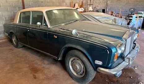 Rolls-Royce Silver Shadow de 1974 bleu foncé à toit beige, découverte poussiéreuse dans un garage.