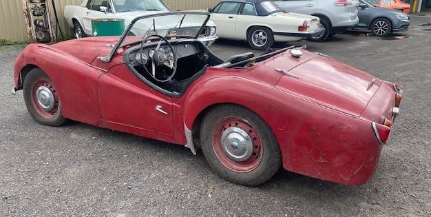 Triumph TR3A de 1959 rouge, roadster britannique ancien à restaurer, photographié de trois quarts arrière.