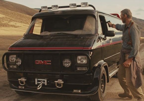GMC Vandura noir à bande rouge dans le film L'Agence tous risques de 2010, avec un personnage près de la portière.