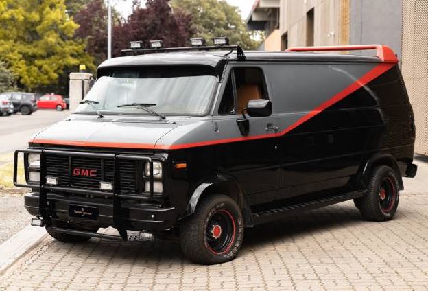 Réplique du GMC Vandura de L'Agence tous risques, avec peinture noire et grise, bande rouge, pare-buffle et aileron arrière.