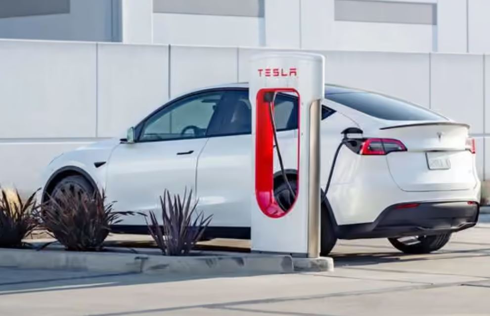 Tesla Model Y électrique devant une borne de recharge Supercharger